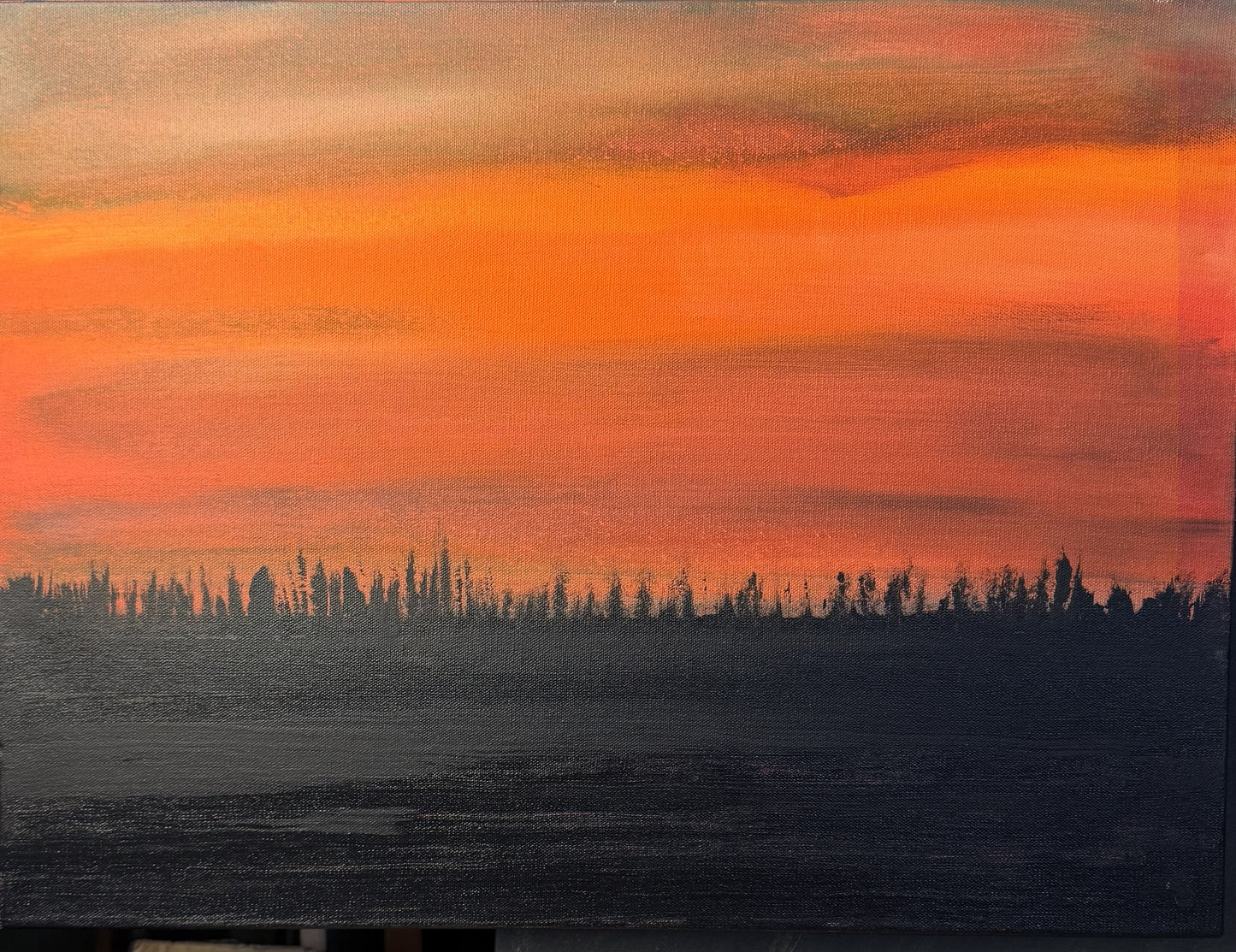 Surreal landscape with orange sky and dark silhouette of trees